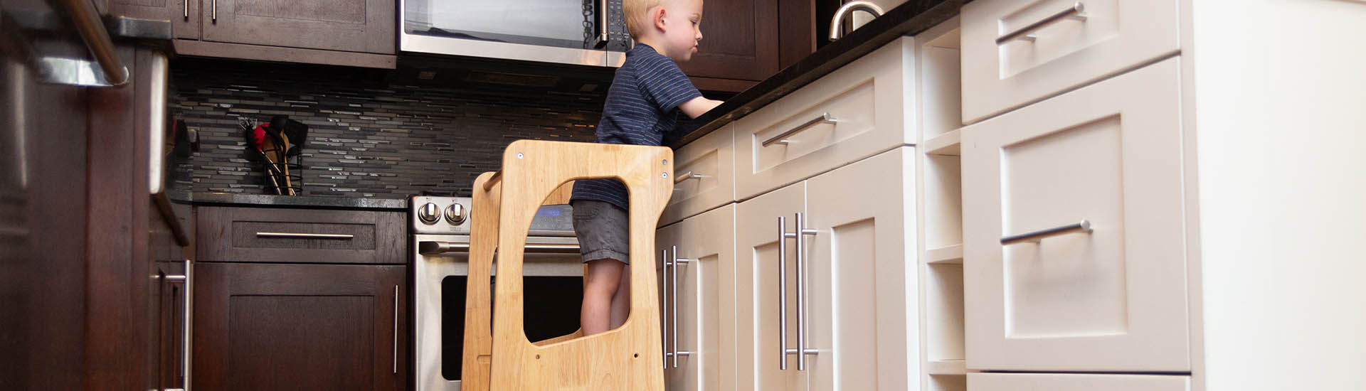 Boy standing on kids kitchen step stool helper